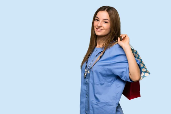 Молода Медсестра Тримає Багато Сумки Покупок Ізольованому Синьому Фоні — стокове фото