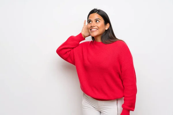 耳に手を置くことによって何かを聞いて赤いセーターを持つコロンビア少女 — ストック写真