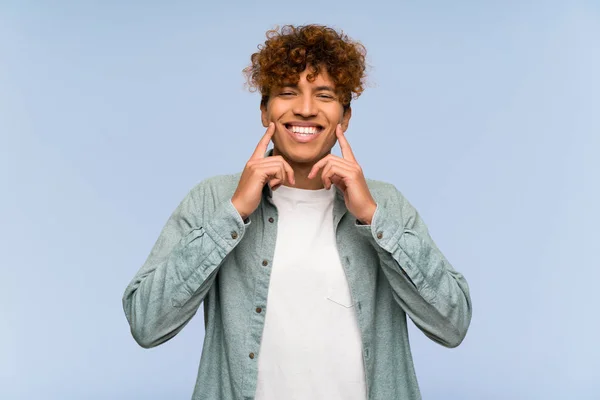 Young african american man over isolated blue wall smiling with a happy and pleasant expression