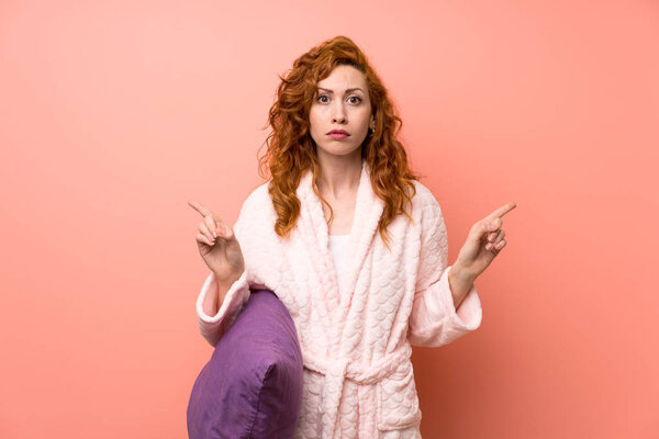 Redhead woman in dressing gown pointing to the laterals having doubts