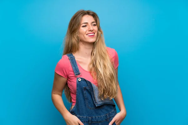 Genç Sarışın Kadın Mavi Duvardan Sarkık Elbisesiyle Gülümsüyor — Stok fotoğraf