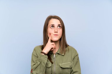 İzole mavi duvar üzerinde genç kadın bir fikir düşünme