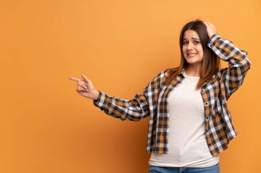 Kahverengi duvarın arkasında genç bir kadın var.