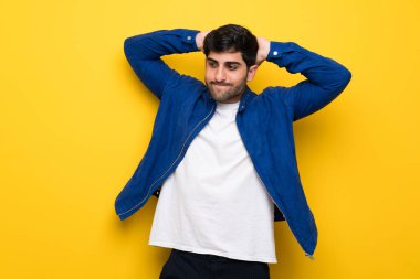 Sarı duvar üzerinde mavi ceketli adam sinirli ve kafasına el ele alır