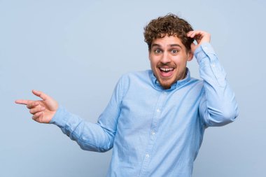 Mavi duvar şaşırmış ve işaret parmak yanına sarışın adam