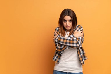 Kahverengi duvarda donmakta olan genç bir kadın.