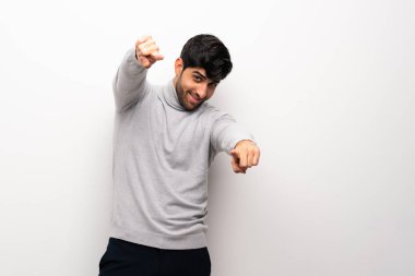 İzole edilmiş beyaz duvardaki genç adam gülümserken seni işaret ediyor.