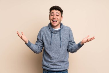 Şok yüz ifadesi ile izole duvar üzerinde genç adam