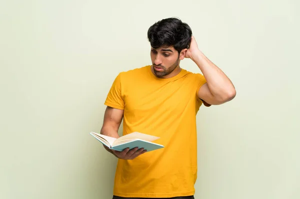 Młody Człowiek Nad Różową Ścianą Zaskoczony Czytając Książkę — Zdjęcie stockowe
