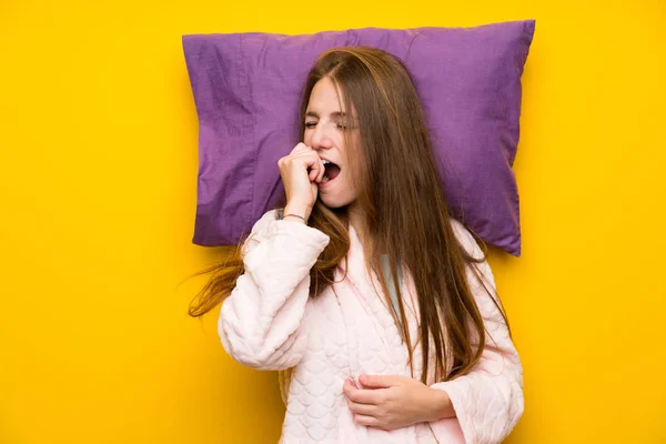 Young woman in dressing gown in a bed yawning