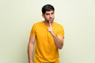 Genç adam pembe duvarın üzerinde ciddi ve ön tarafı işaret ediyor.