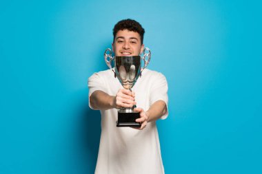 Mavi renkli bir kupa tutan genç adam