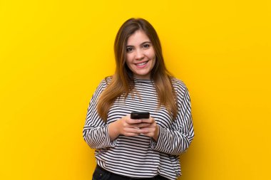 Sarı duvar üzerinde genç kız cep ile bir mesaj gönderme