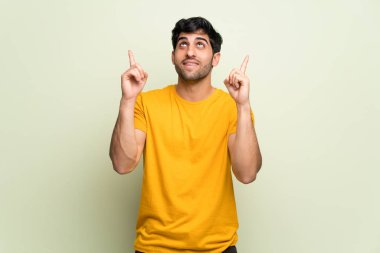 Pembe duvarın üstünde işaret parmağıyla işaret eden genç adam harika bir fikir.