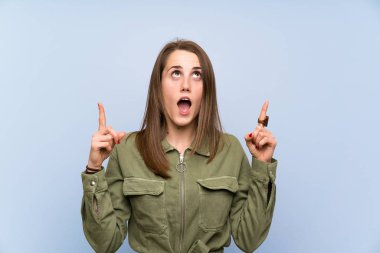 İşaret parmağı ile işaret izole mavi duvar üzerinde genç kadın harika bir fikir