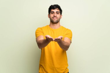 Pembe duvar üzerinde genç adam bir reklam eklemek için palmiye üzerinde boşaltmak hayali tutarak