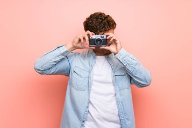 Pembe duvar bir kamera tutarak sarışın adam