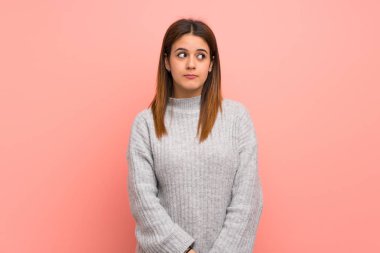 Pembe duvarın arkasında genç bir kadın şüpheli hareketler yapıyor.