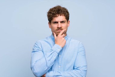 Sarışın adam mavi duvarın şüpheleri üzerinden