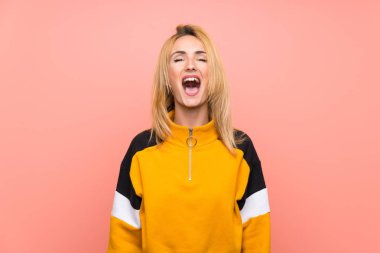 Soyutlanmış pembe arka planda genç sarışın kadın ağzı açık bağırıyor.