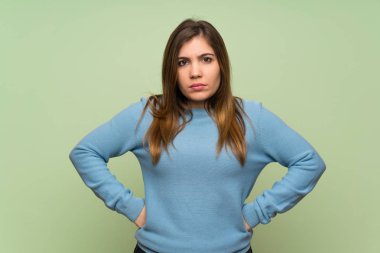 Young girl over green wall angry