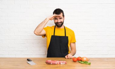 Şef bir şey bakmak için el ile uzak görünümlü bir mutfak tutarak