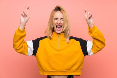 İzole edilmiş pembe arka planı olan genç sarışın kadın.