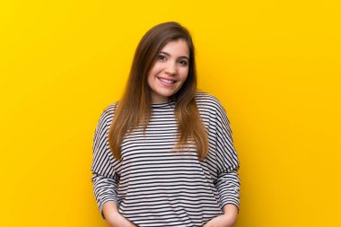 Young girl over yellow wall laughing