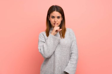 Pembe duvarın üstünde genç bir kadın sessizlik işareti gösteriyor. Parmağını ağzına sok.