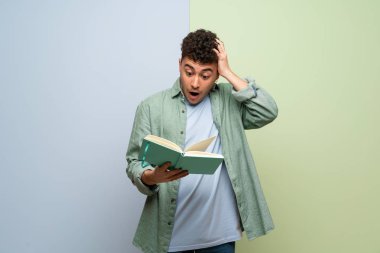 Mavi ve yeşil geçmişi olan genç adam kitap okumaktan zevk alırken şaşırdı.