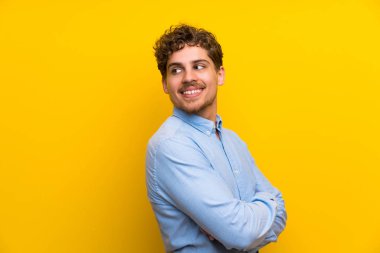 Sarışın adam gülüyor izole sarı duvar üzerinde