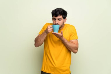 Pembe duvar kahve bir fincan sıcak tutan genç adam