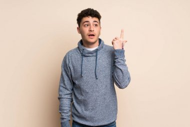 İzole duvar üzerinde genç adam parmak işaret bir fikir düşünme