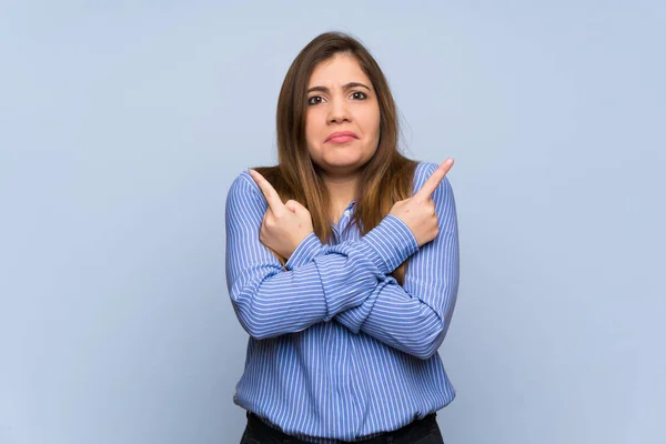 Young Girl Isolated Blue Wall Pointing Laterals Having Doubts — Stockfoto