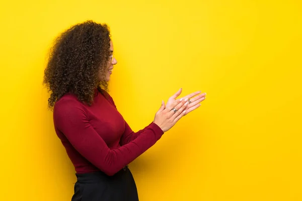 Dominican woman with turtleneck sweater applauding after presentation in a conference