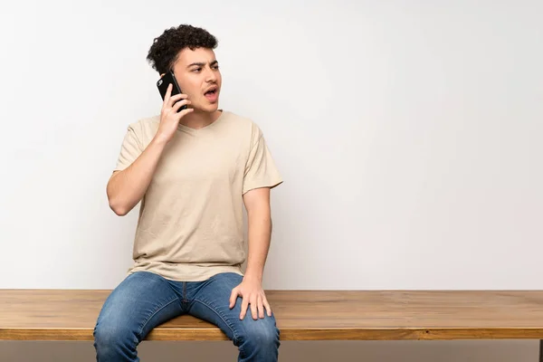 Jovem Sentado Mesa Mantendo Uma Conversa Com Celular — Fotografia de Stock