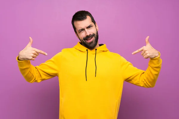 Handsome man with yellow sweatshirt proud and self-satisfied