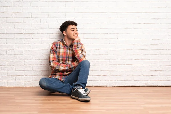 Junger Mann Sitzt Auf Dem Boden Und Schaut Zur Seite — Stockfoto