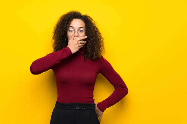 Dominican woman with turtleneck sweater covering mouth with hands for saying something inappropriate