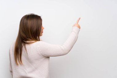 Young girl with white sweater pointing back with the index finger