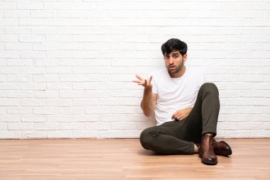 Açık kat yapma oturan genç adam jest şüphe ediyor.