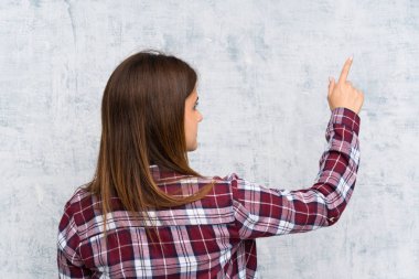 Duvarın üzerinde genç bir kadın işaret parmağıyla işaret ediyor.