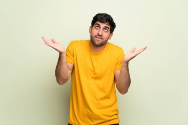 Genç adam pembe duvarın üzerinden omuzlarını kaldırırken önemsiz bir jest yapıyor.