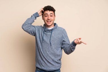 İzole duvar üzerinde genç adam sürpriz ve tarafına parmak işaret