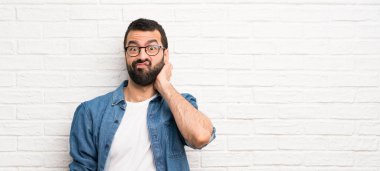 Beyaz tuğla duvar üzerinde sakallı yakışıklı adam şüpheleri olan