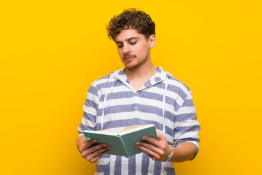 Bir kitap ve okuma zevk sarı duvarın üzerinden sarışın adam