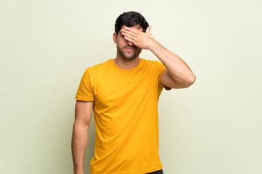 Pembe duvarın üzerinden gözlerini elleriyle kapayan genç bir adam. Bir şey görmek istemiyorum.