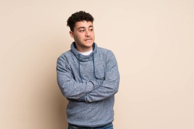 Kafası karışmış genç bir adam, izole edilmiş bir duvar üzerinde.