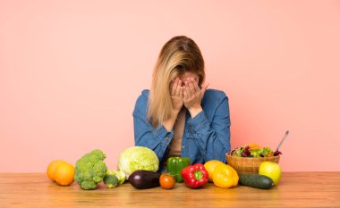 Yorgun ve hasta suratlı, bir sürü sebzeli genç sarışın kadın.