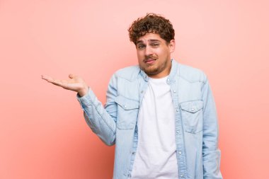 Copyspace hayali tutarken pembe duvar üzerinde sarışın adam ciddi